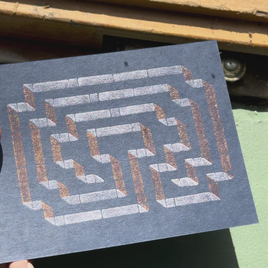 Print of a labyrinth on a piece of dark blue cardstock using Tsukineko Brilliance Cosmic Copper and Platinum Planet ink colors