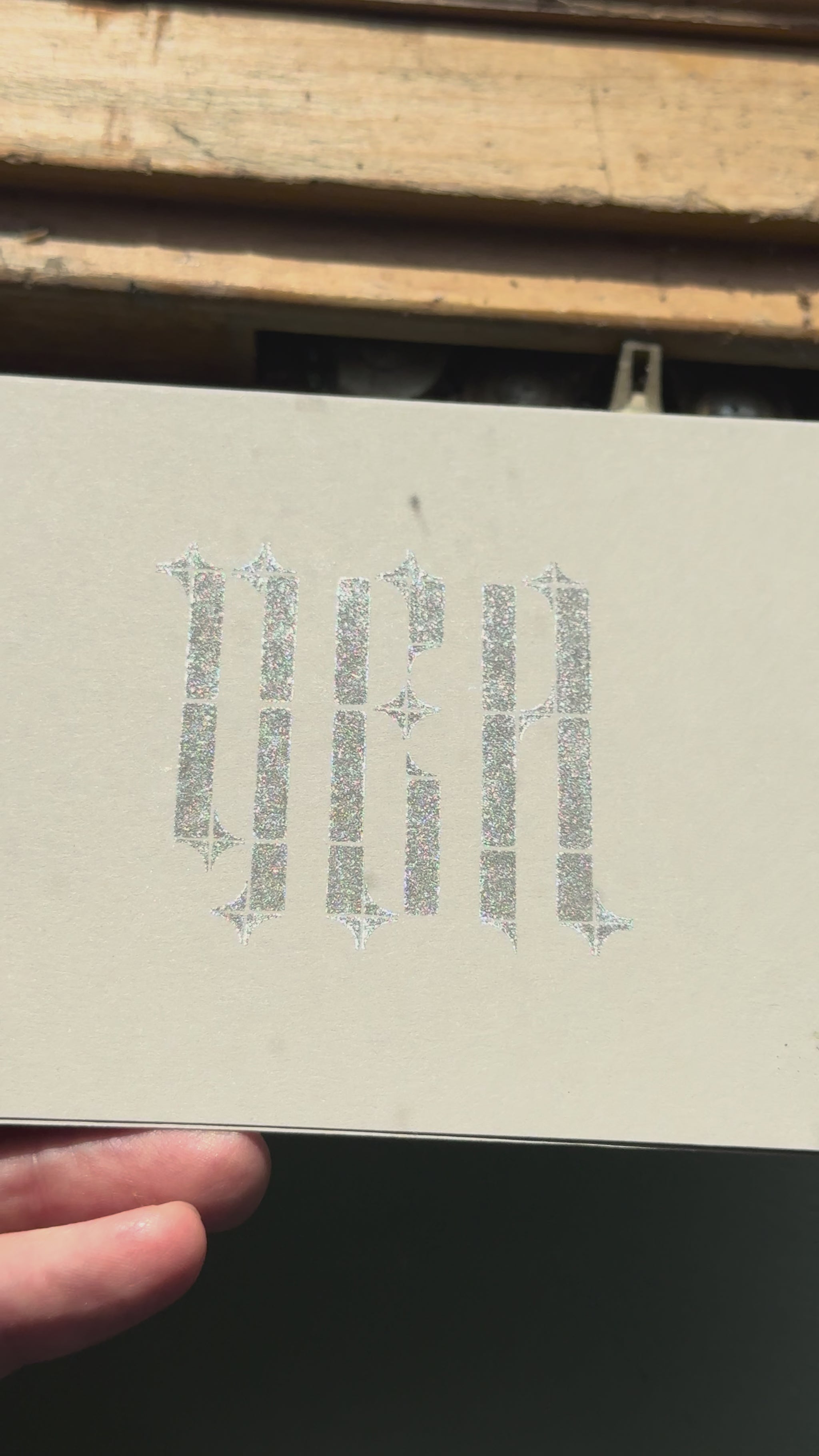 Print of the word "YEA" in a gothic typeface on a piece of gray cardstock using Tsukineko Brilliance Starlite Black ink